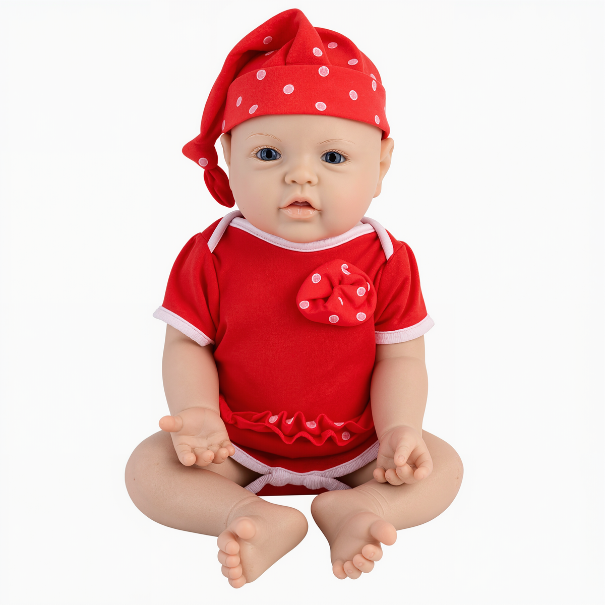 A realistic baby doll wearing a red short-sleeve romper and matching red hat with white polka dots, posed against a plain white background.